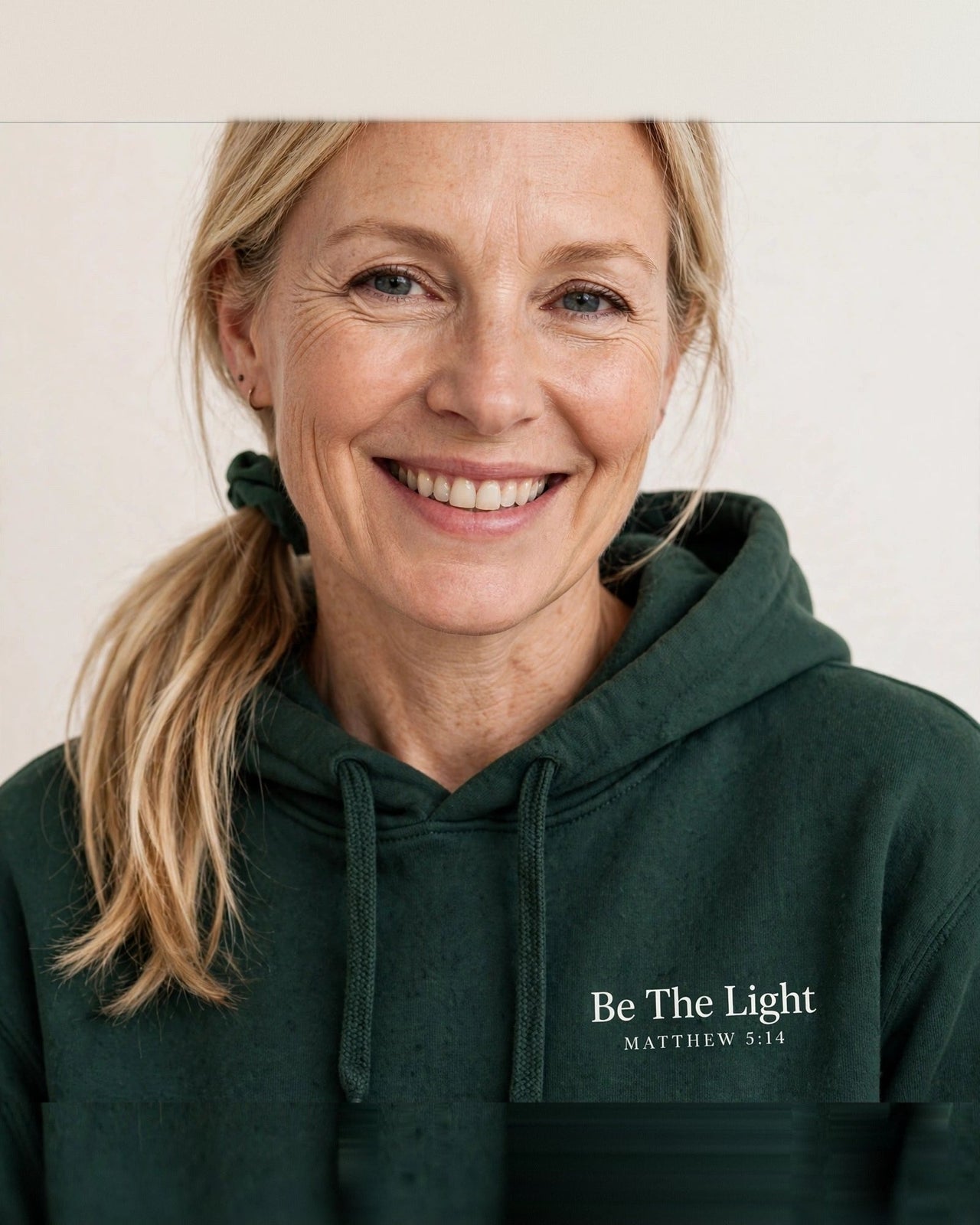 Woman wearing the Be The Light hoodie in dark green