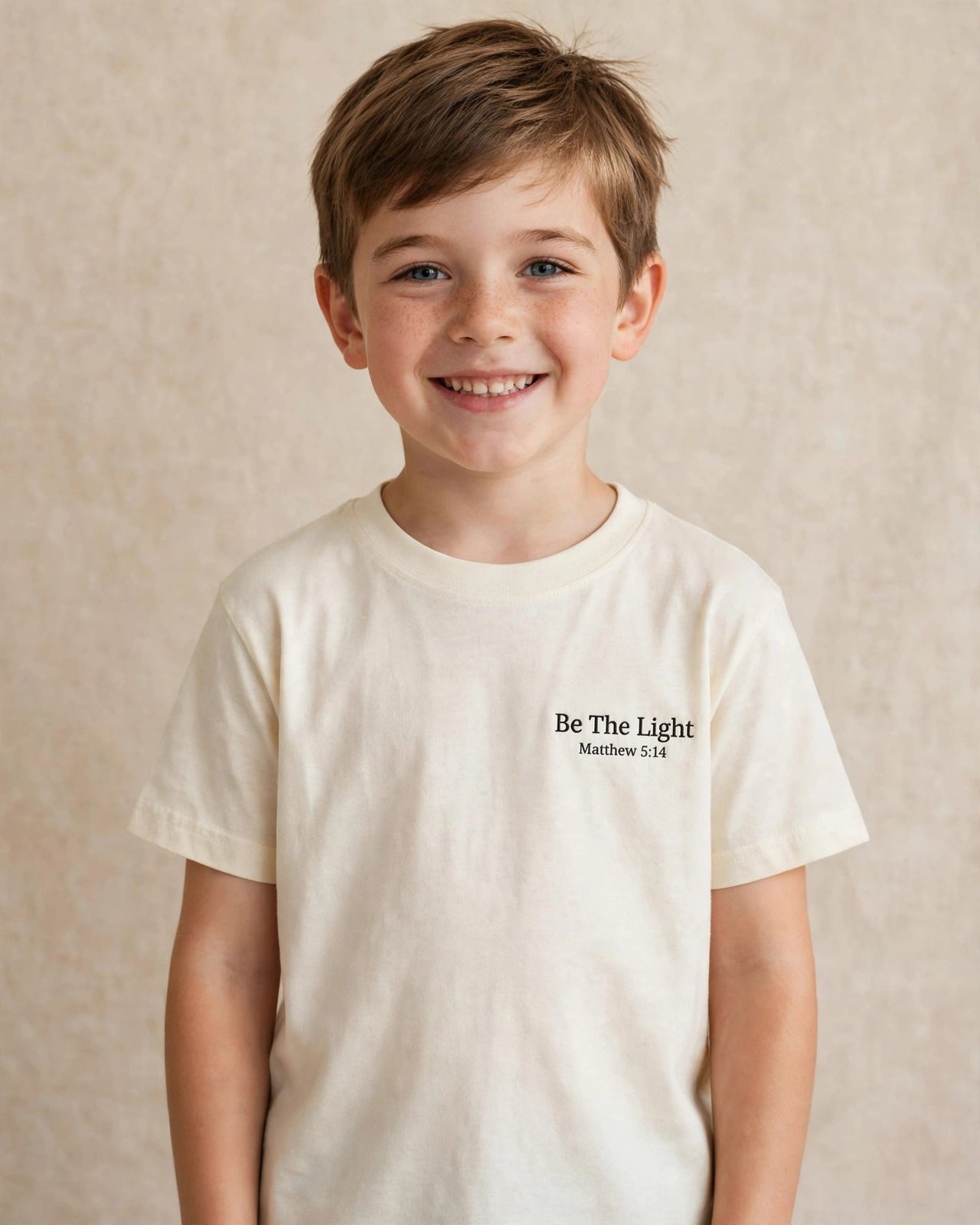 Child wearing the cream Kids Be The Light Tee - Be The Light, Matthew 5:14 print over the heart